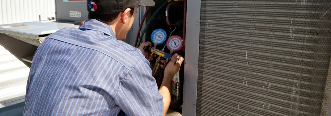 HVAC technician servicing a condenser unit in Perry